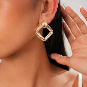 Gros plan de boucles d'oreilles losanges dorées à double couche portées par un modèle