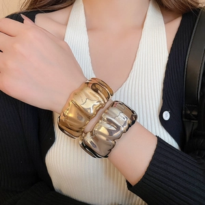 Détail de bracelets manchettes larges avec texture froissée en finitions or et argent