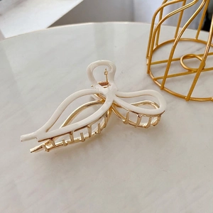 Detailed close-up of cream-colored acetic acid bow hair claw with gold metal finish