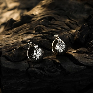 Vintage silver lava texture hoop earrings displayed on dark charred wood background