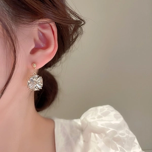 Gros plan d'une boucle d'oreille fleur dorée avec pendentif en cristal sur un mannequin