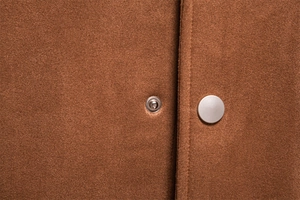 Détail des boutons-pression en métal argenté et texture du tissu suédé marron
