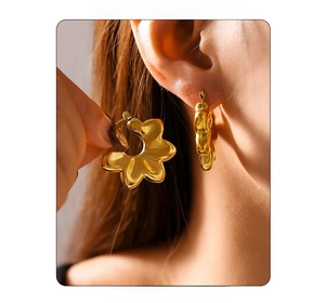 Detailed close-up of golden wavy petal-shaped earrings on a model in natural light