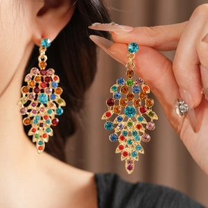 Detail of vintage style gold leaf earrings with colorful rhinestones on a female model