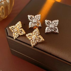 Macro view of gold and silver hollow flower earrings with sparkling cubic zirconia inlay