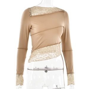 Detail of beige cropped long sleeve top with intricate lace stitching and irregular hem