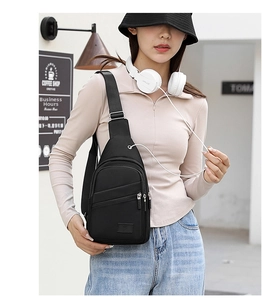 Close-up of black Oxford fabric chest bag showing dual zippers and side headphone port