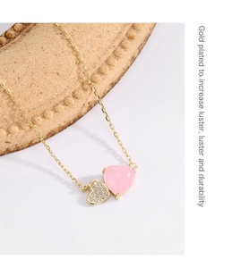 Detailed macro of gold-plated double heart pendant with pavé crystals and pink pearl finish