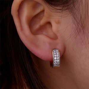 Close-up of gold U-shaped huggie earrings with double row cubic zirconia on ear