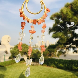 Detail of natural crystal suncatcher moon wind chime with orange stones and butterfly beads