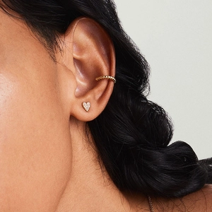 Elegant gold heart stud earrings and beaded ear cuff set on a model ear
