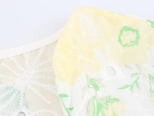 Close-up of floral embroidery and hollow lace detail on a yellow v-neck dress