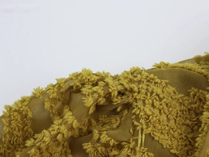 Macro shot of yellow-green textured mesh fabric with 3D tufted patterns on the blouse