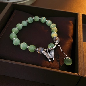 Détail de bracelet en perles œil-de-chat avec pendentif papillon en argent poli