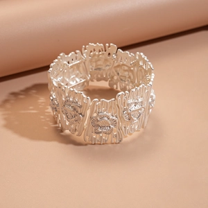 Detailed macro of silver wide bracelet with embossed floral pattern and bark texture