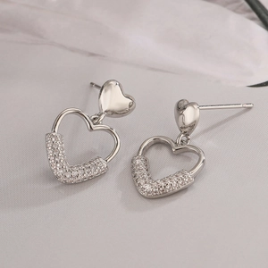 Détail de boucles d'oreilles cœur argentées avec pavage de zircons brillants