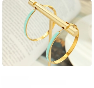 Macro shot of gold hoop earrings with light blue enamel and secure lever back closure
