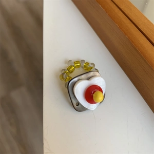 Detail of handmade beaded ring featuring layered heart motif and translucent yellow beads