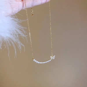 Detail of 18k gold butterfly necklace featuring sparkling zircons and elegant white pearls