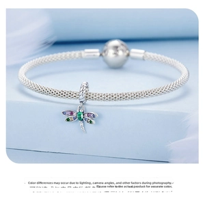 Macro detail of S925 silver dragonfly charm with colorful cubic zirconia on a mesh bracelet