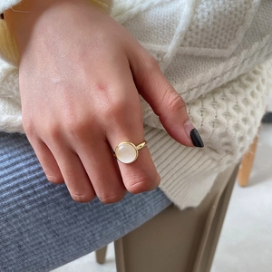 Detailed view of a gold S925 silver ring featuring a round white opal on a finger