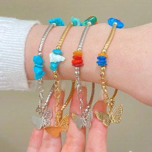 Détail de bracelets bohèmes superposés avec pierres colorées et papillons
