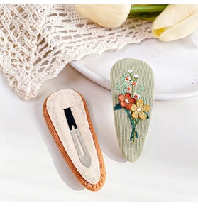 Detailed front and back views of embroidered fabric flower hair clips for children
