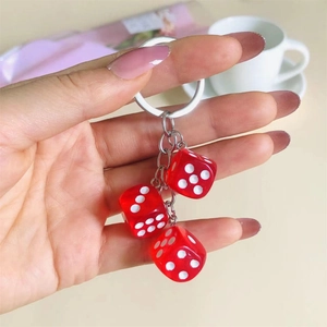 Close-up of metal keychain with three transparent red resin dice pendants in a lifestyle setting