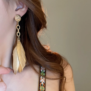 Detail of long gold chain earrings with leaf shape on model showing texture and length