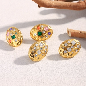 Nahaufnahme goldener Edelstahlohrstecker mit bunten Kristallen und Textur
