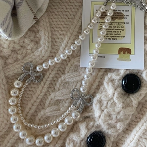 Détail d'un élégant collier de perles à deux rangs avec des nœuds en strass scintillants