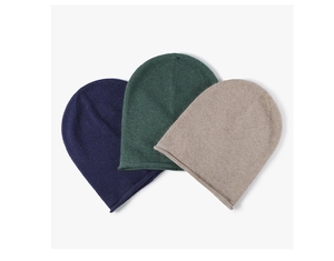 Detail view of winter knit beanies in navy blue, green, and beige wool textures