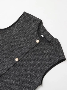 Dettaglio colletto gilet in tweed con bottoni dorati e trama bianco e nero