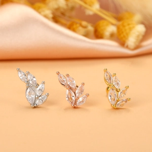 Macro shot of three leaf-shaped stud earrings in silver, gold, and rose gold finishes