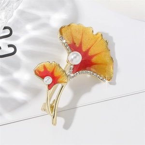 Ginkgo leaf brooch with colorful enamel and pearls on a clean white studio background