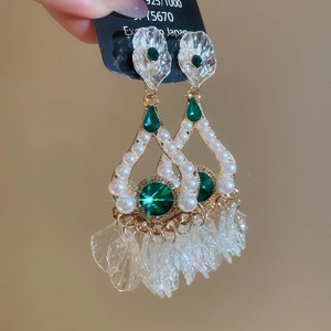 Detail of emerald green stones and white pearls on vintage gold chandelier earrings