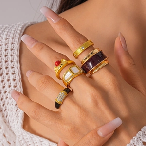 Macro shot of gold-plated rings with enamel inlay and rhinestone details on model