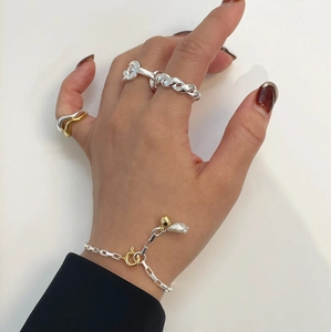 Detail of twisted silver chain ring and mixed-tone wavy ring with pearl bracelet