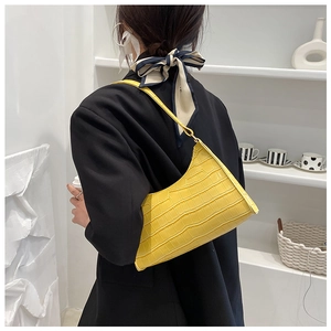 Bright yellow crocodile pattern underarm bag shown on a model in a black blazer