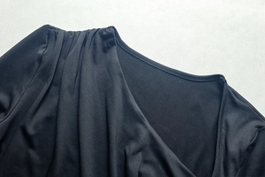 Detail of elegant black dress showing ruched shoulder and asymmetrical neckline design