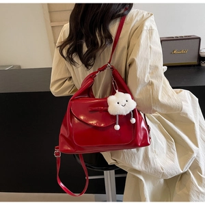 Detail of red patent leather shoulder bag with a cute white cloud plush pendant charm