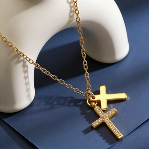 Detail of gold double cross necklace featuring one polished and one crystal-paved pendant