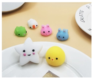 Close-up of colorful TPR squishy animal toys including chicks and stars on a ceramic plate