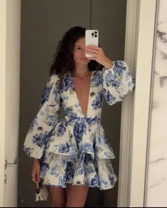 Detail of blue and white floral V-neck dress with layered ruffle hem and puff sleeves