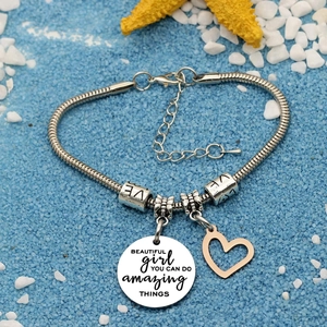 Inspirational snake chain bracelet with engraved heart charm on beach sand background