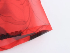 Gros plan détaillé du tissu organza rouge semi-transparent aux motifs floraux noirs