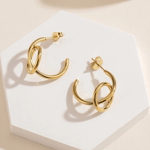 Detail of 14K gold plated stainless steel C-shape earrings on a geometric display