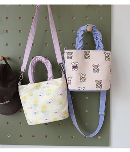 Detail of canvas bucket bags with ruffle handles in pastel yellow and soft pink colors