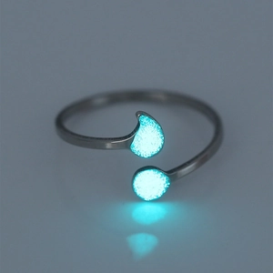 Macro shot of silver open ring with glowing blue-green drop and circle shapes
