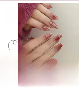 Detail of red gradient press-on nails with plaid patterns, white hearts, and rhinestones